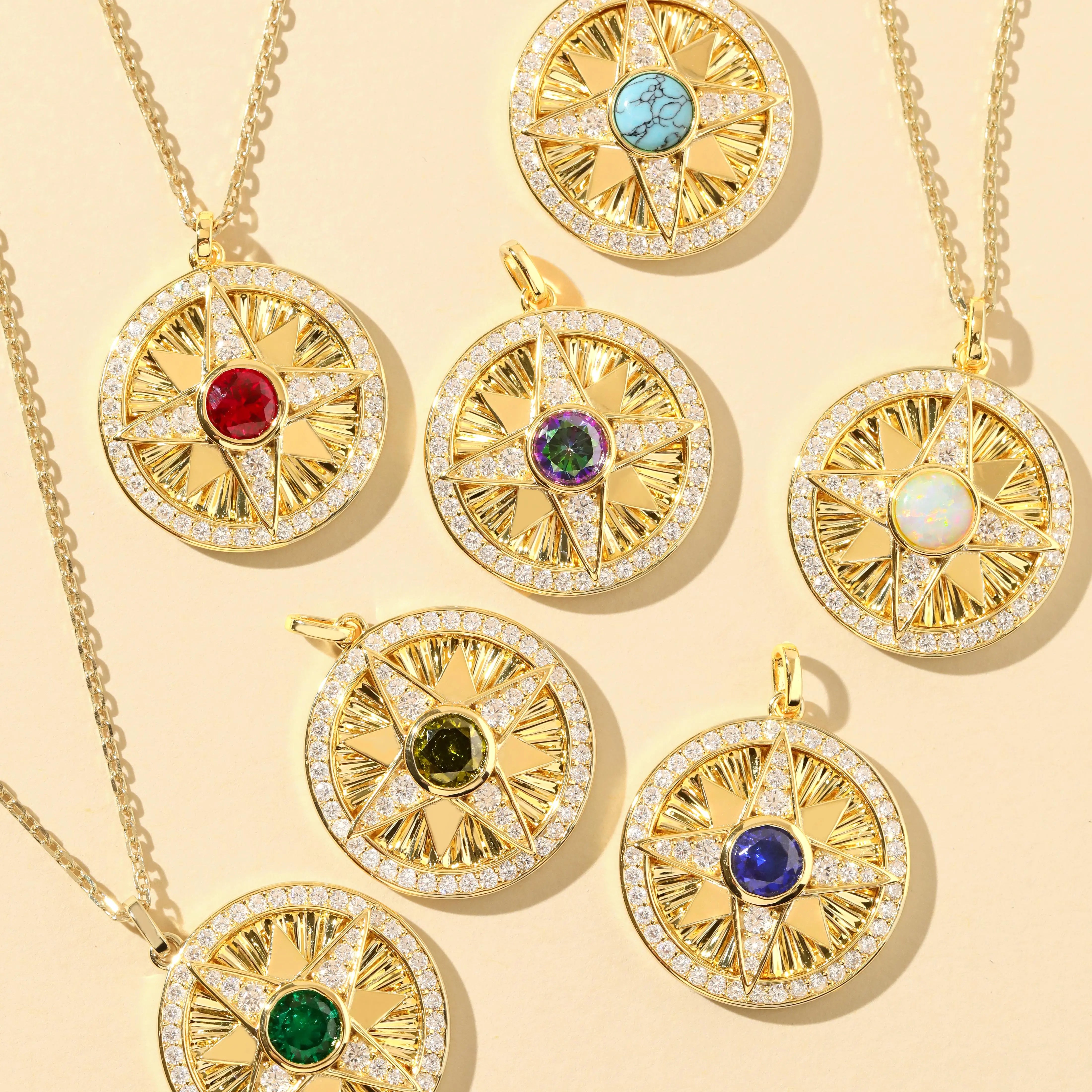Collection of gold compass necklaces with multi‑color gemstone center stones